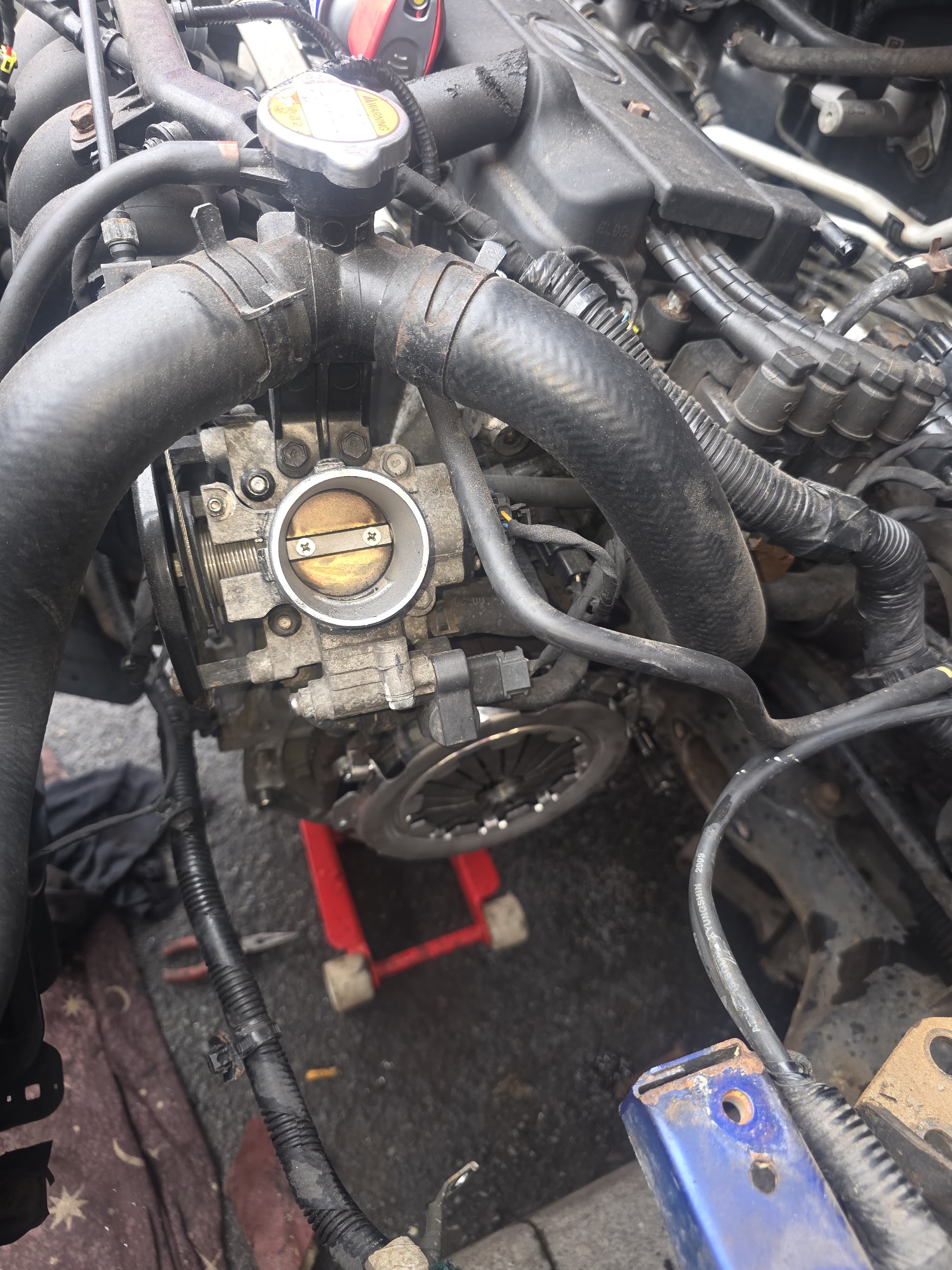 Clutch and throttle body visible in an engine bay on the ground