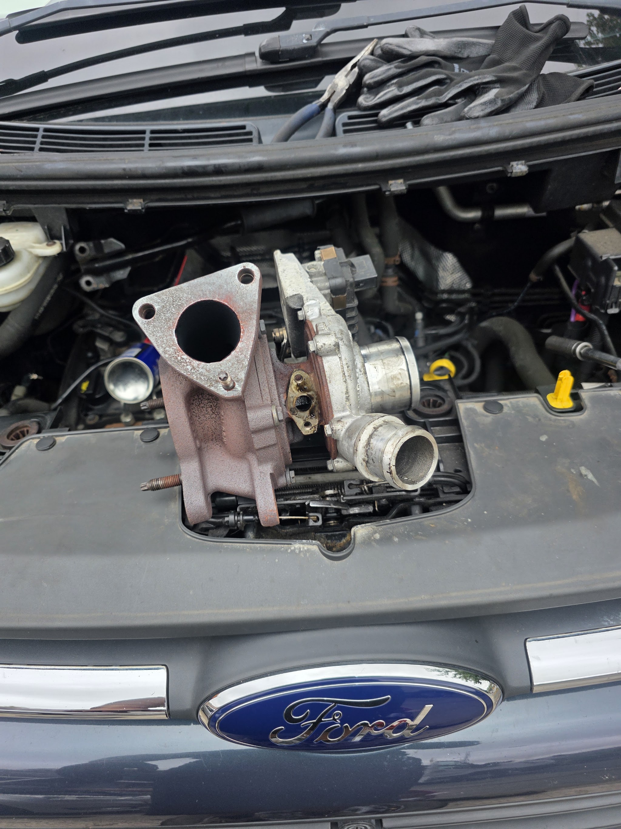 A turbocharger removed from a Ford engine and resting on the engine cover